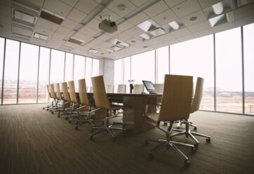 Conference room with a large table and chairs against a wall of windows.