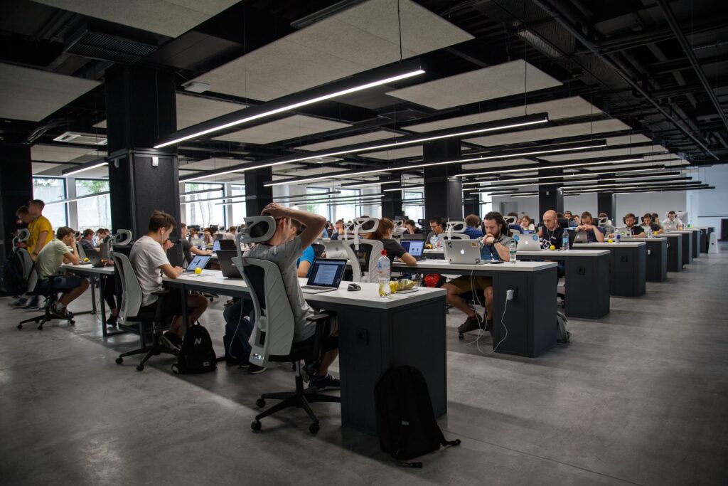Open office with rows of tables, computers and employees.