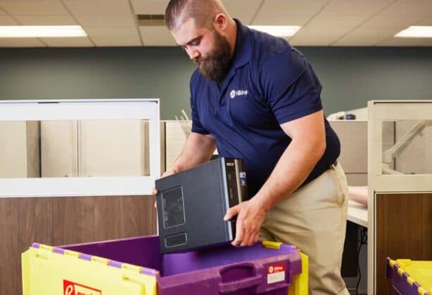 worker placing a computer into a crate to move