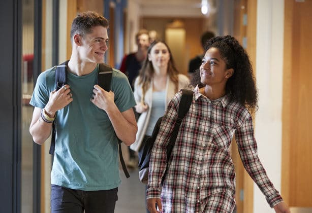 students walking down the hallway with backpacks on