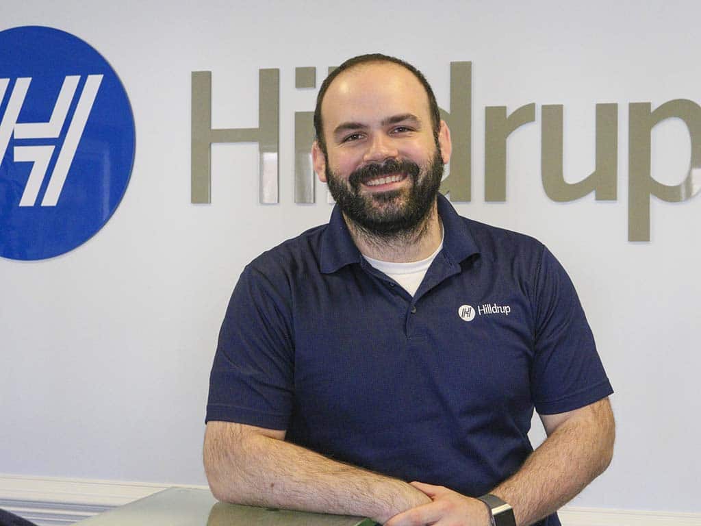 Hilldrup employee smiling in front of Hilldrup sign