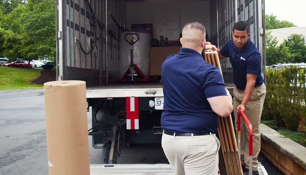 Two men loading boxes into truck