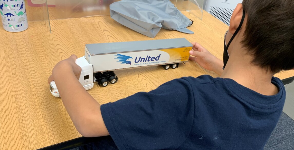 A student at FA looks at a toy truck of a Hilldrup tractor trailer