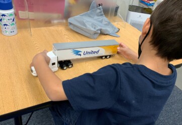 A student at FA looks at a toy truck of a Hilldrup tractor trailer