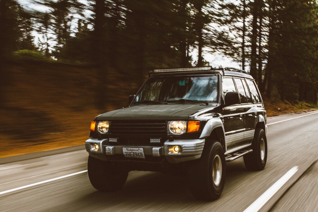 Green SUV on highway in forest