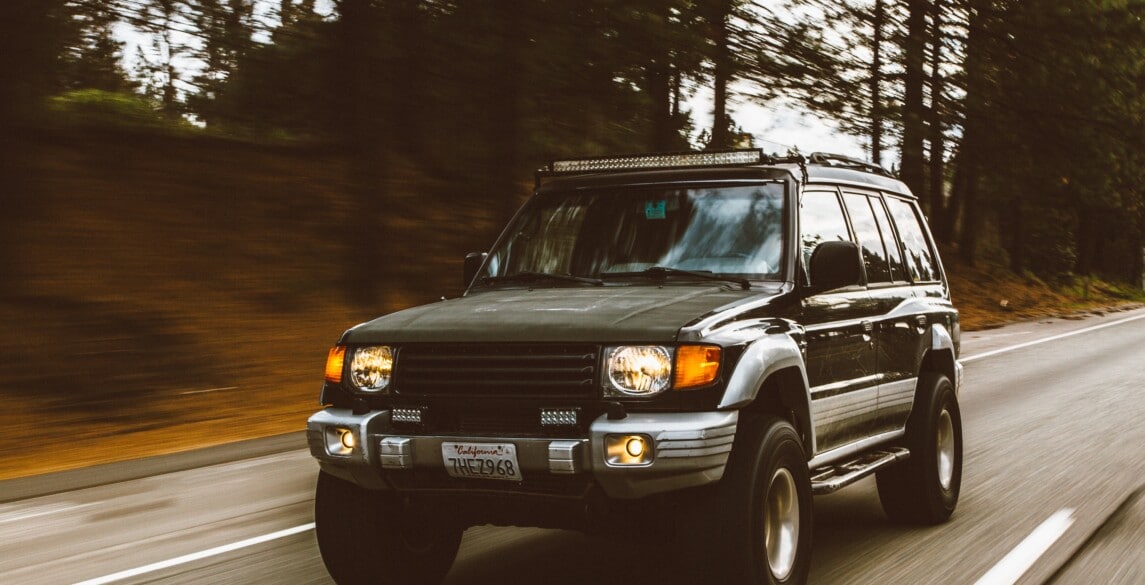 Green SUV on highway in forest