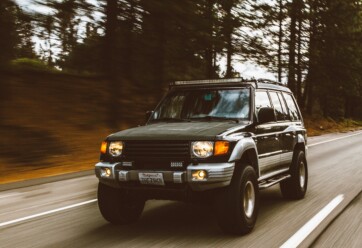 Green SUV on highway in forest