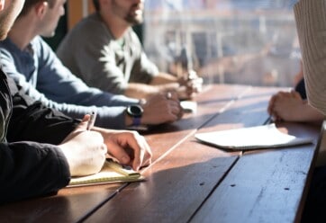 Group of coworkers sitting at a wood table.