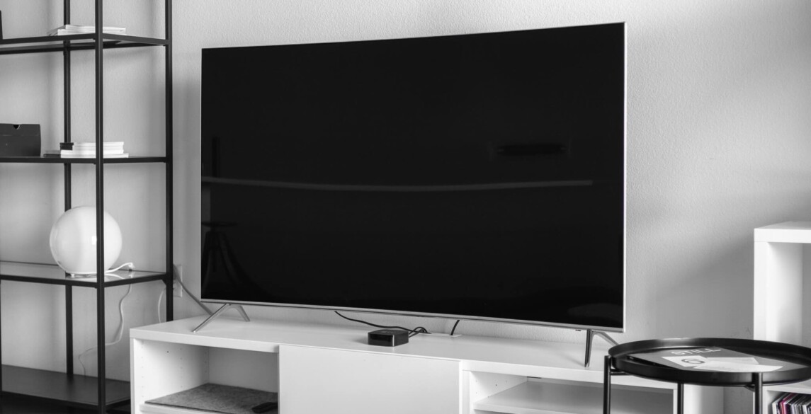 Large TV on a wall above a white entertainment console.