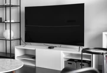 Large TV on a wall above a white entertainment console.