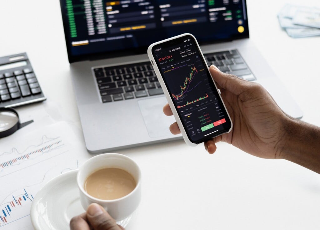 Person reviewing data on phone with cup of coffee.