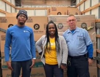 Hilldrup service team members with RUW representative with our fleet and boxes of donated toilet paper.