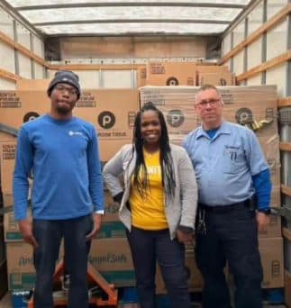 Hilldrup service team members with RUW representative with our fleet and boxes of donated toilet paper.