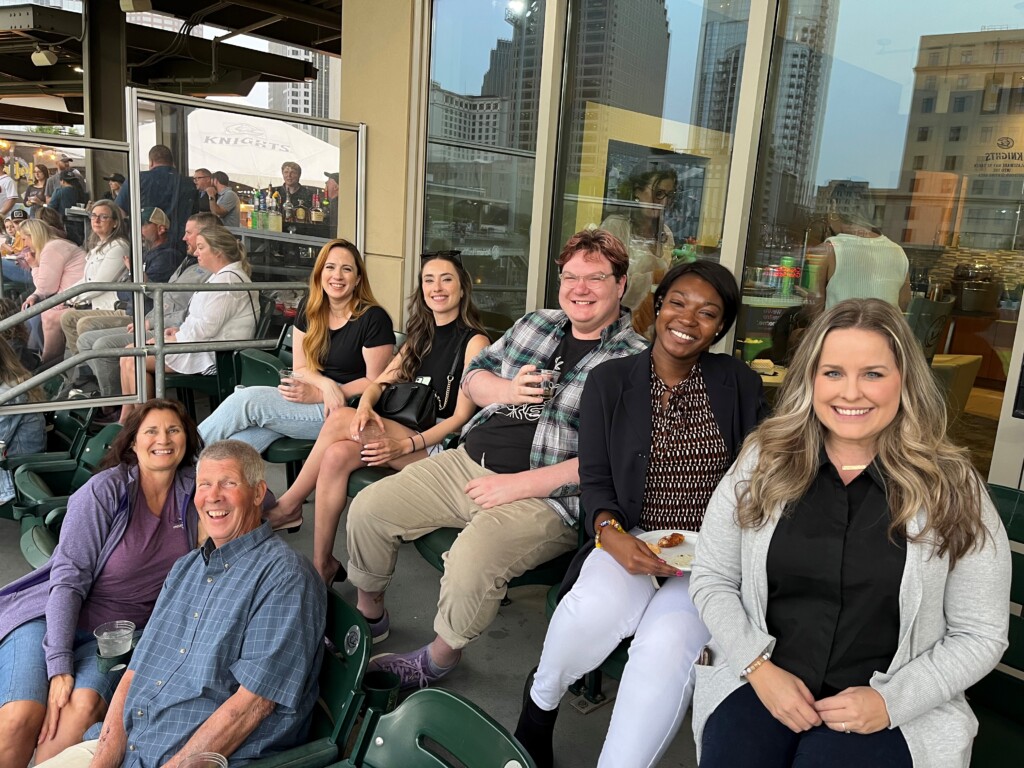 Attendees sitting in the stands at Molly's networking baseball event. 