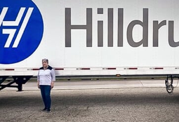 Brenda Harless standing by Hilldrup truck