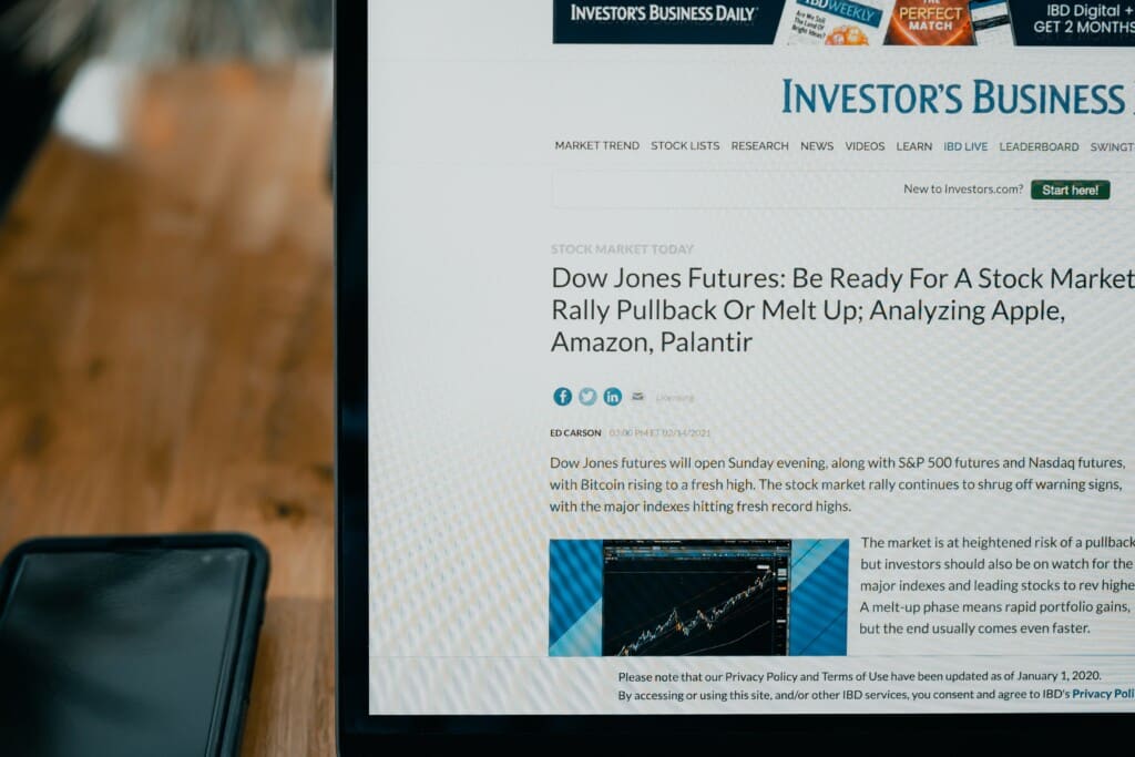 An open laptop on a desk with an investment news website pulled up.