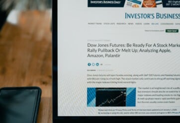 An open laptop on a desk with an investment news website pulled up.