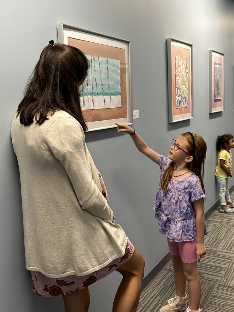 Student artist explaining her artwork on display. 