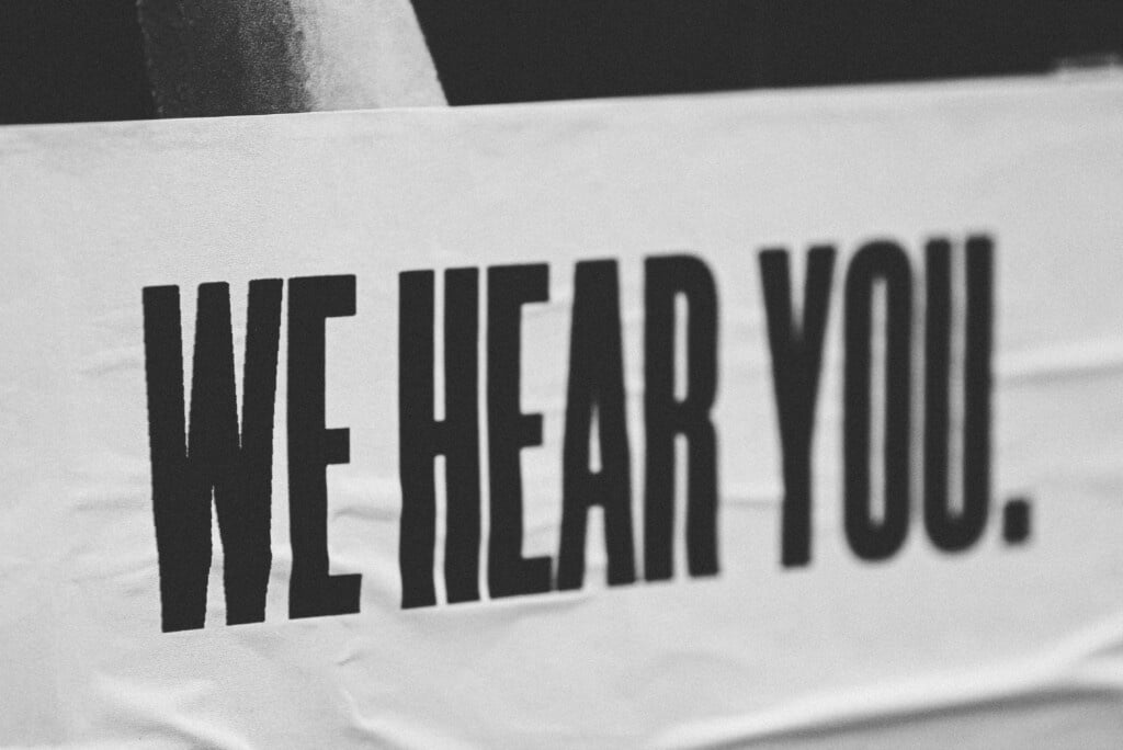 Black and white picture of a banner that says We Hear You.