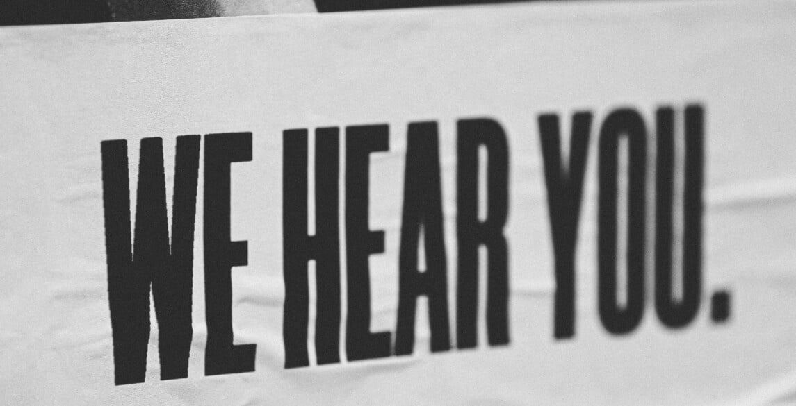 Black and white picture of a banner that says We Hear You.