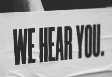 Black and white picture of a banner that says We Hear You.