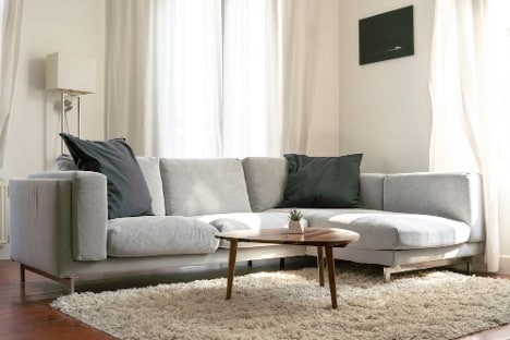 Gray modern couch in living room with wood coffee table in front of it.