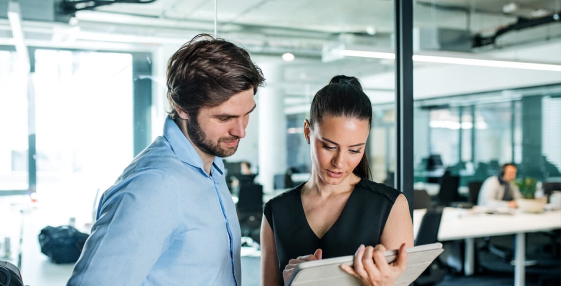 Young businesspeople with tablet standing in an office, working.
