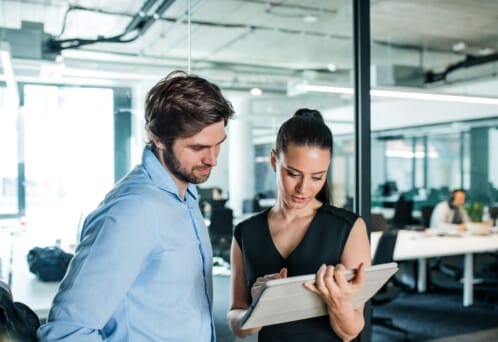 Young businesspeople with tablet standing in an office, working.