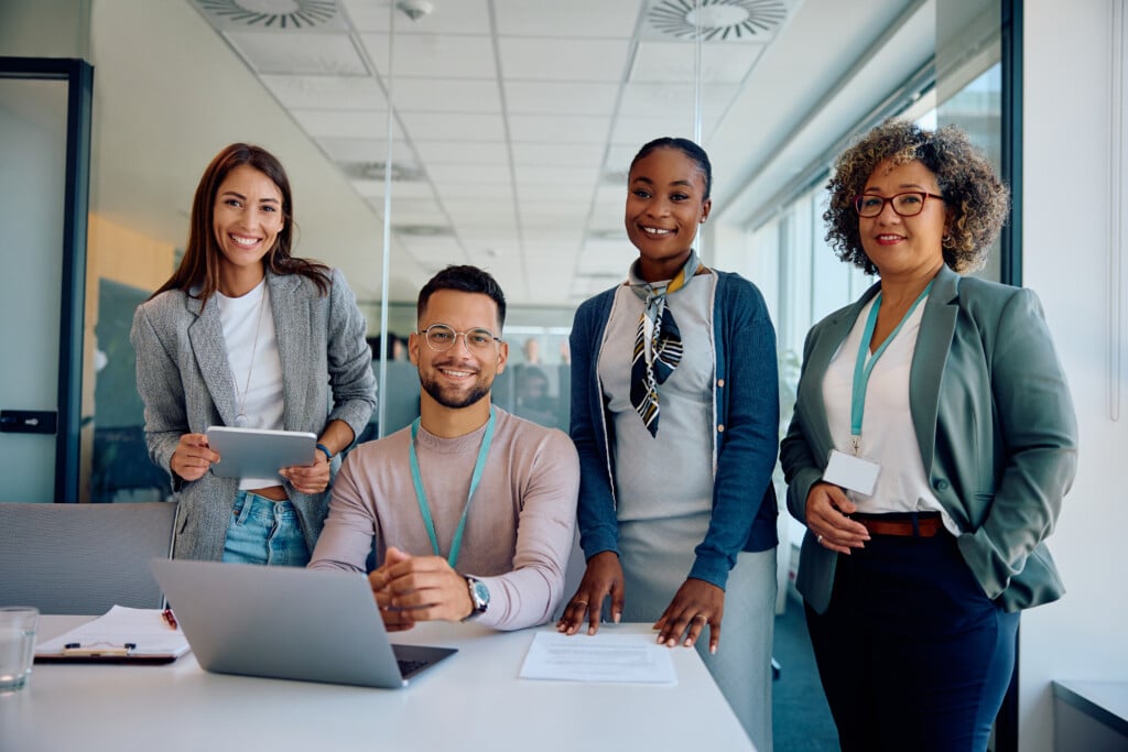 Group of happy business colleagues working at corporate office and looking at camera.