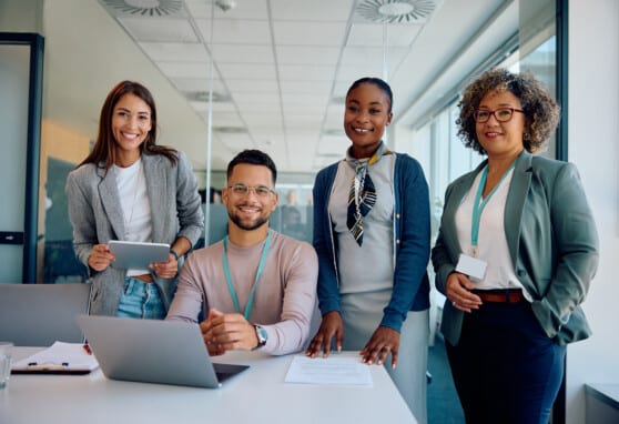 Group of happy business colleagues working at corporate office and looking at camera.