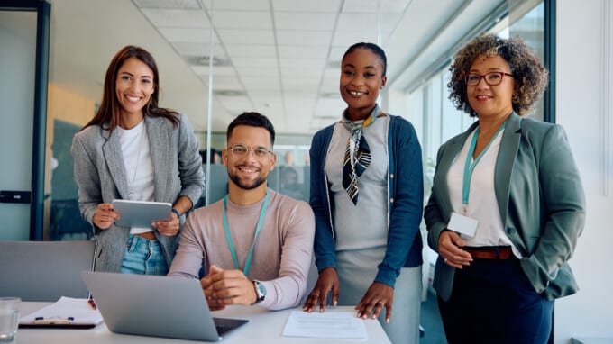 Group of happy business colleagues working at corporate office and looking at camera.
