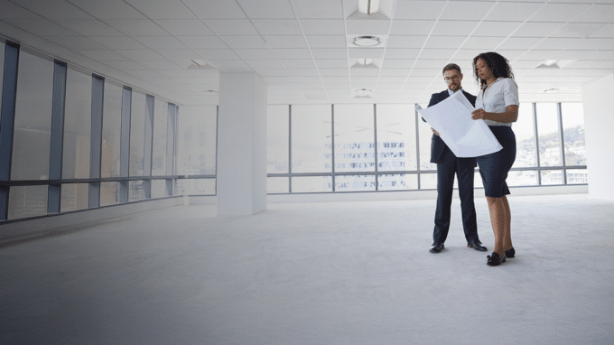 two people looking over plans in an empty office space