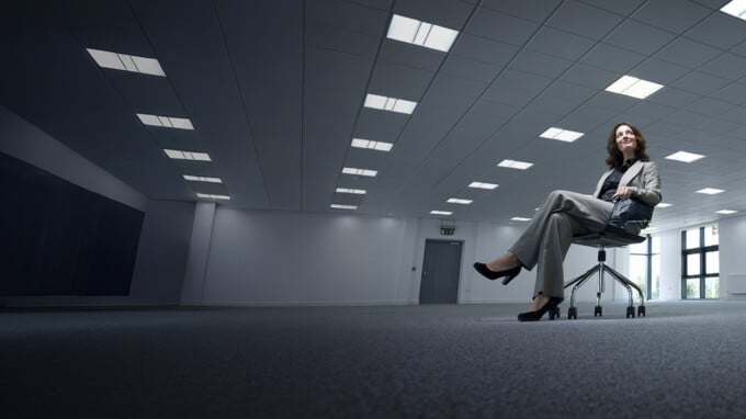 business admin sitting in an office chair in an empty office space, similing