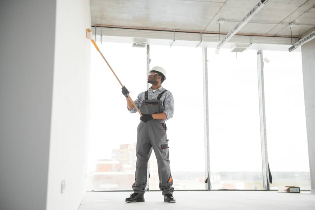 Man paints a white wall with a roller. Repair of the interior.