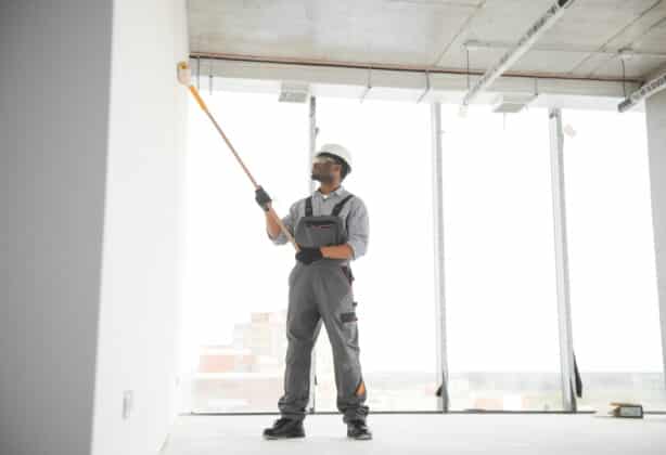 Man paints a white wall with a roller. Repair of the interior.