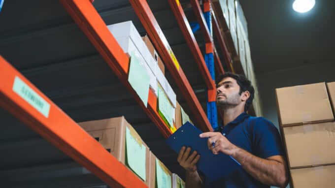 man in warehouse looking at labeled boxes on industrial racks
