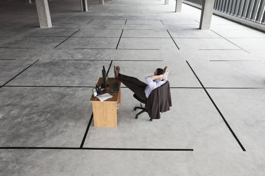 Businessman at desk looking at an empty business space.