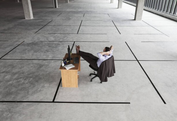 Businessman at desk looking at an empty business space.