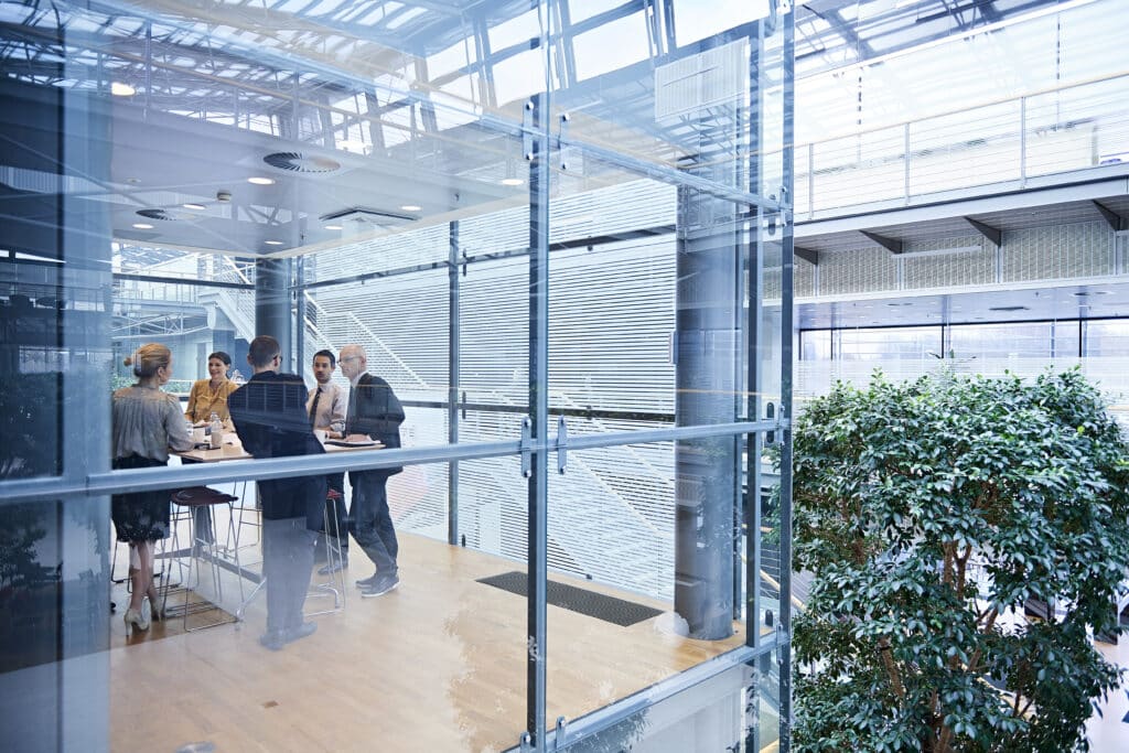 Window view of businesswomen and men having discussion in conference room.