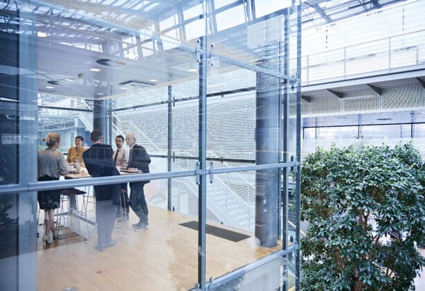 Window view of businesswomen and men having discussion in conference room.