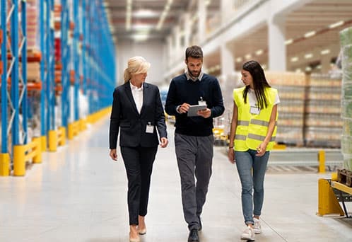 Managers visiting a warehouse with racked storage.