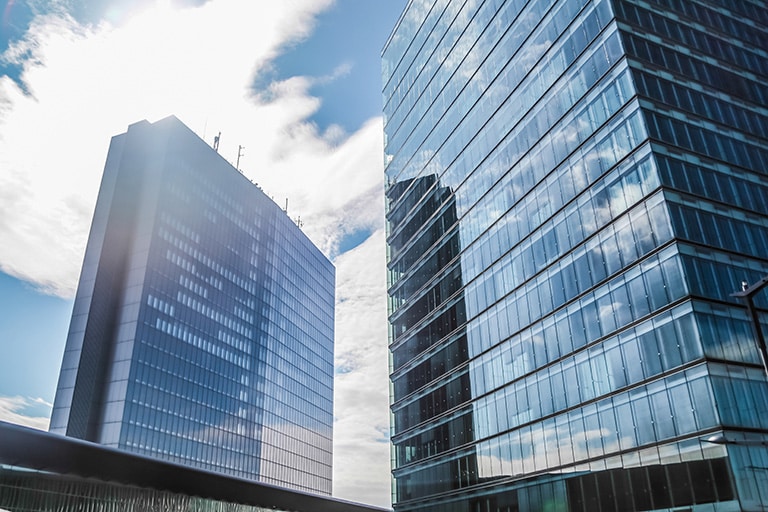 Corporate building with glass windows reflecting nearby business offices. 