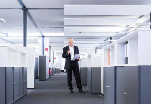 Facilities manager standing between cubicles reviewing premove plan.