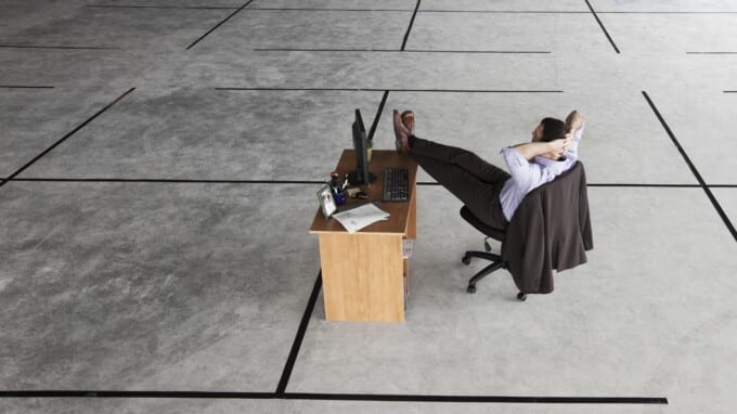 Businessman at desk looking at a new office layout in a large empty business space.