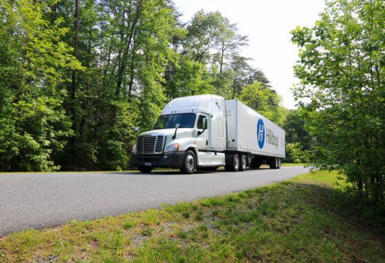 Hilldrup branded truck driving on a rural, wooded road.
