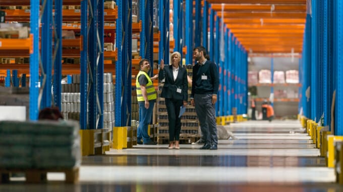 Warehouseman in a large warehouse with commercial racking.